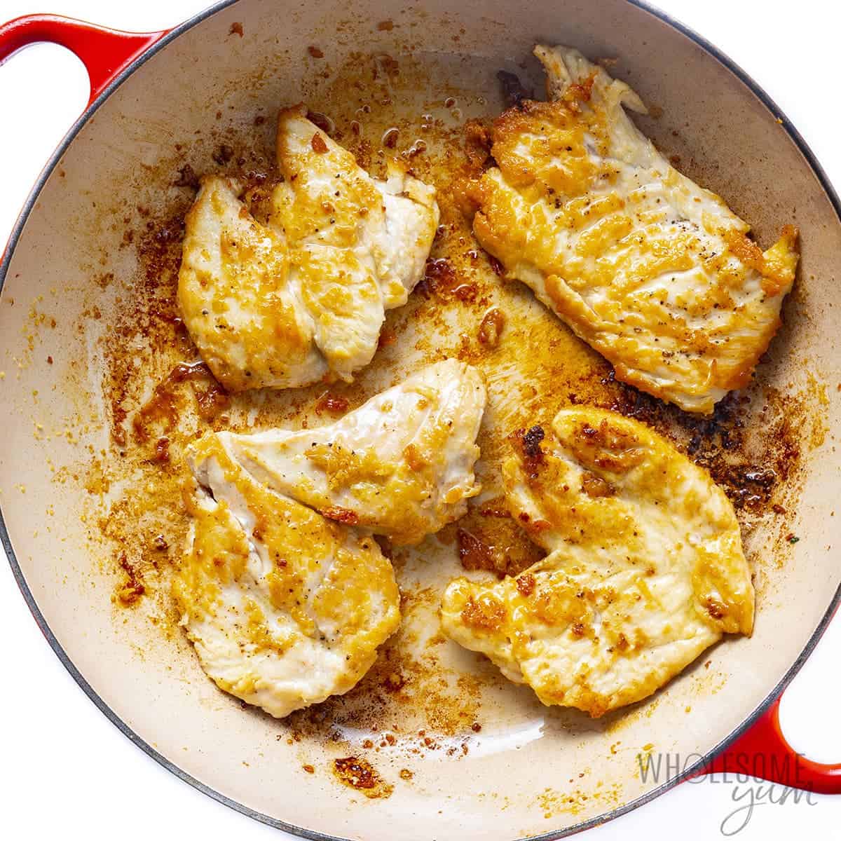 Chicken cutlets frying in pan.