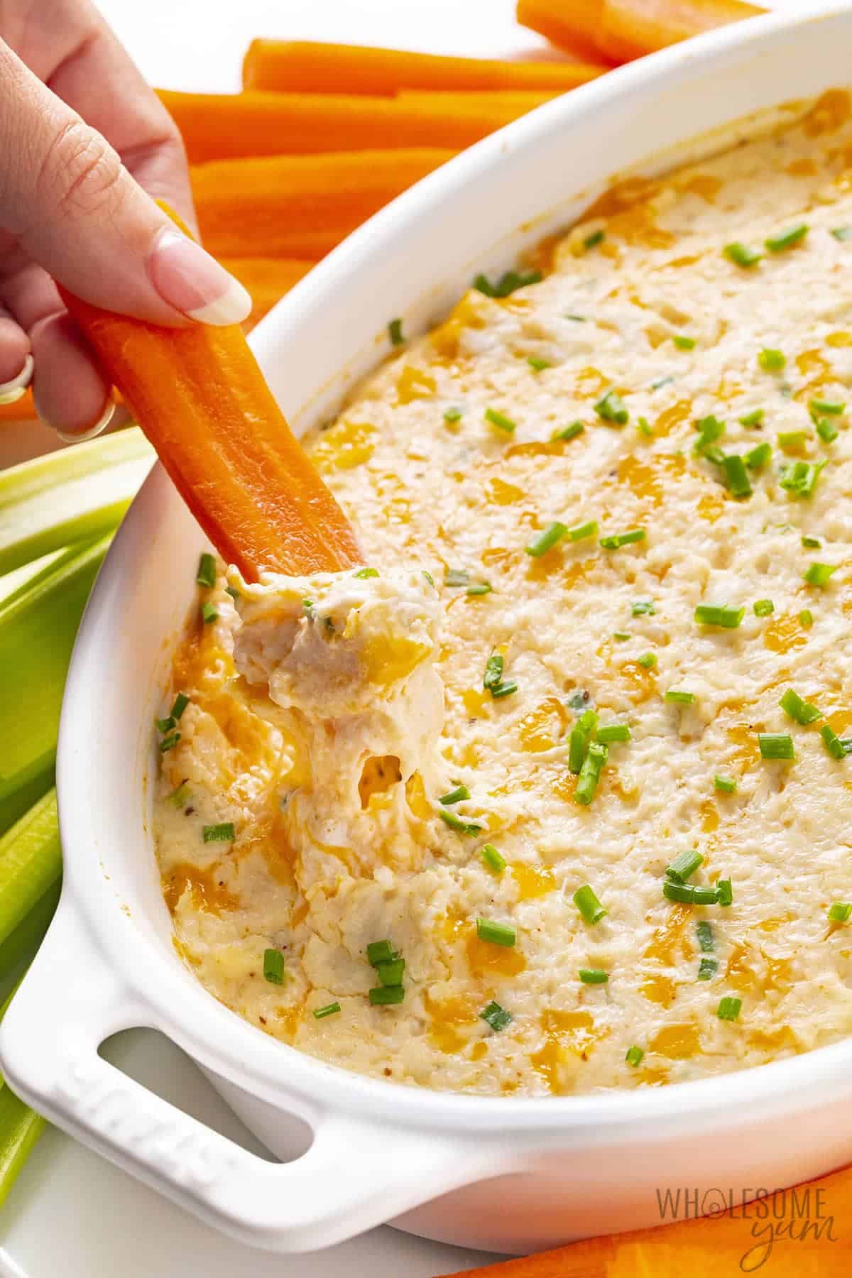 Warm crab dip cheese pull with carrot stick.
