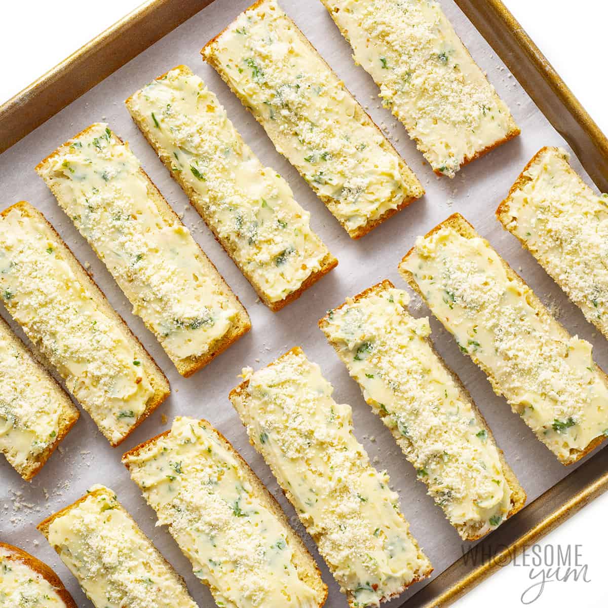 Buttered bread slices on baking pan.