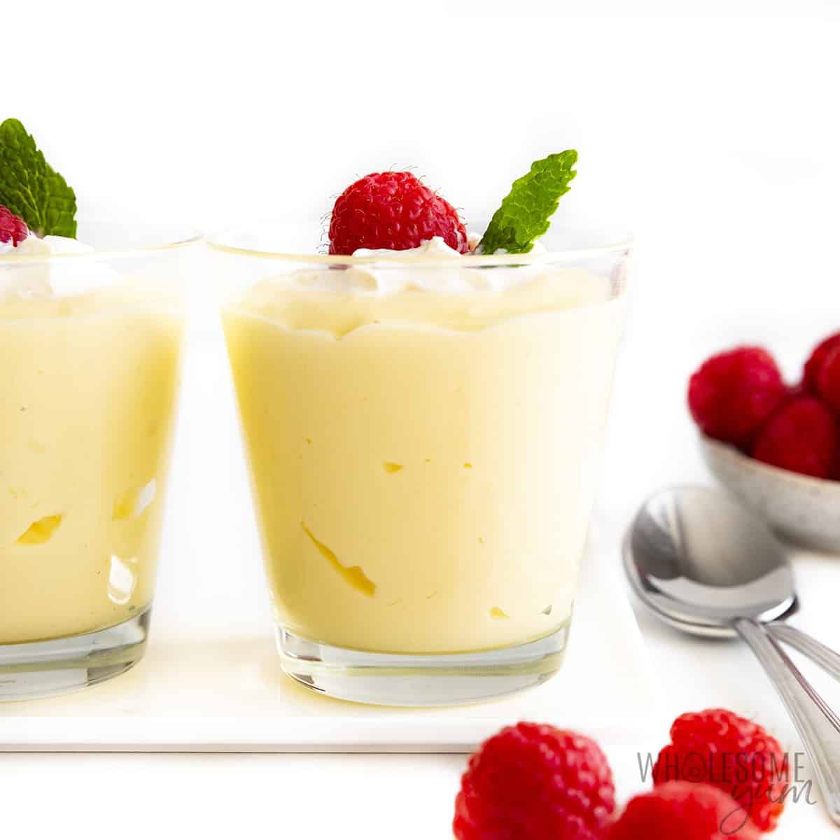 Sugar-free vanilla pudding in cups with raspberries on top.