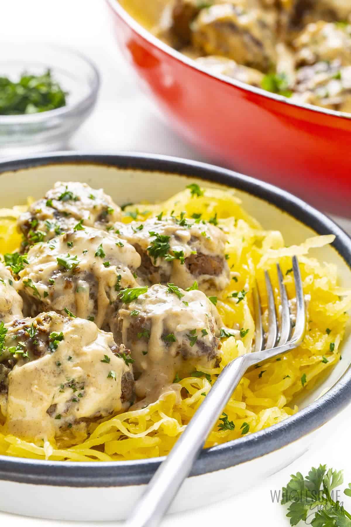 Plate of keto Swedish meatballs with braiser pan in background.