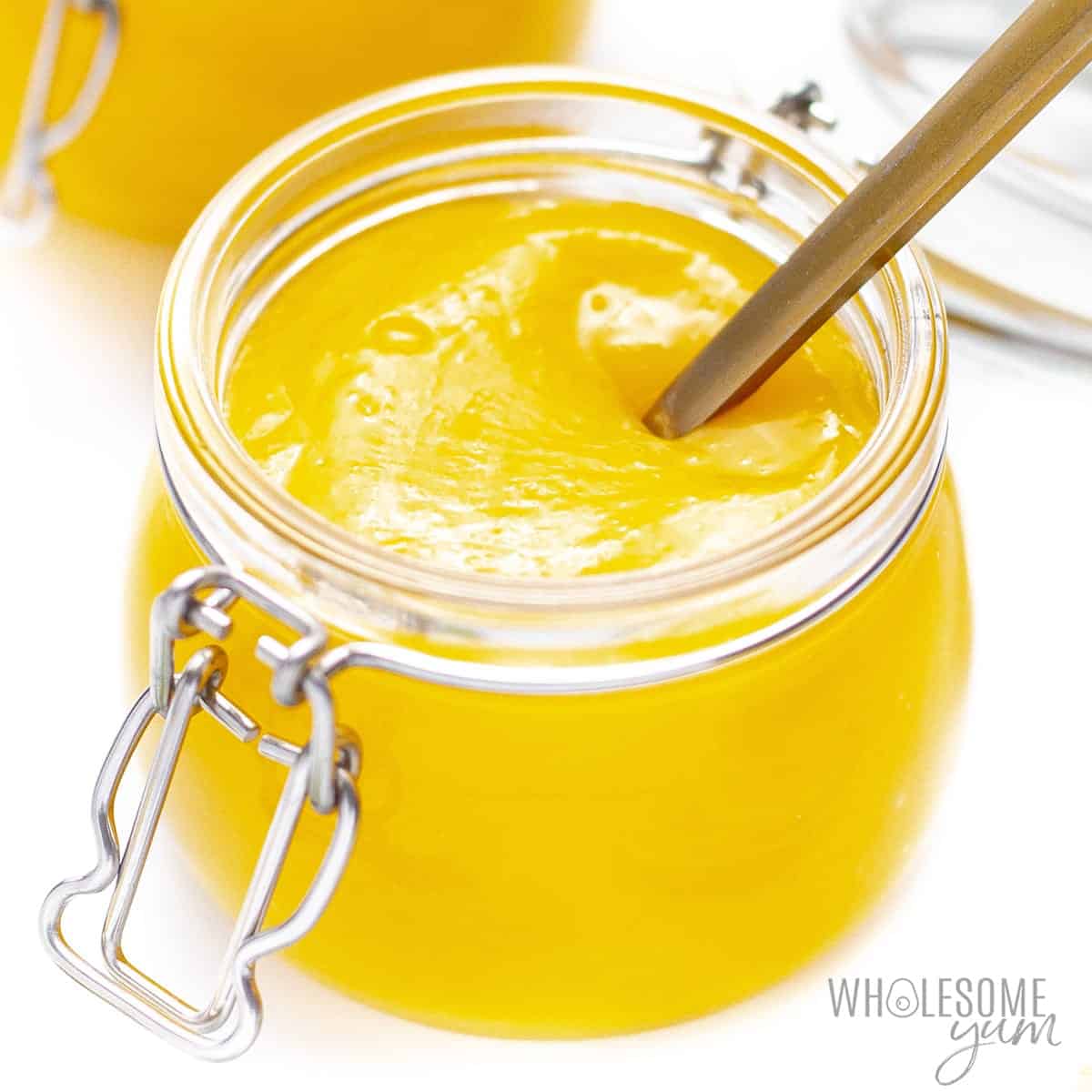 Jar of sugar-free lemon curd with a spoon.