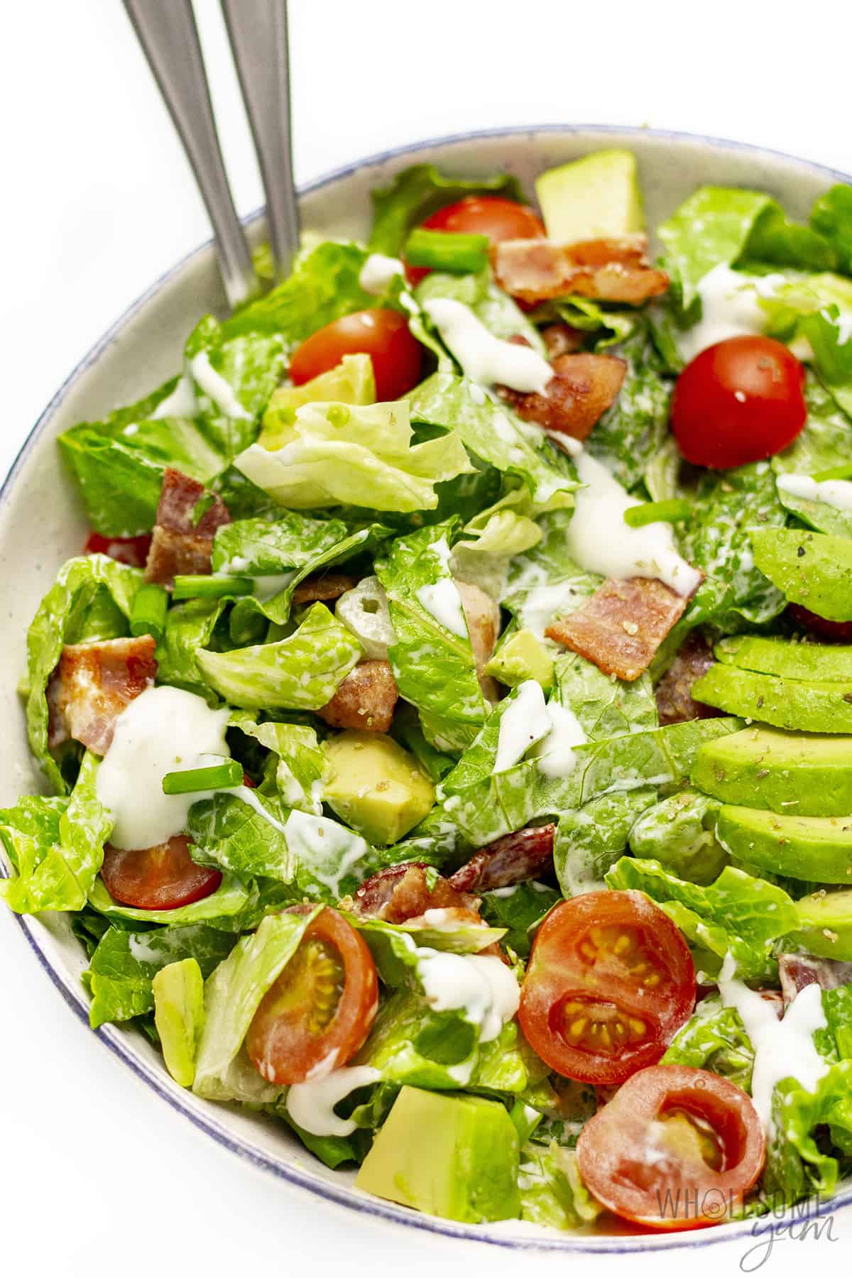 Bacon lettuce tomato salad in a large bowl with serving spoons.