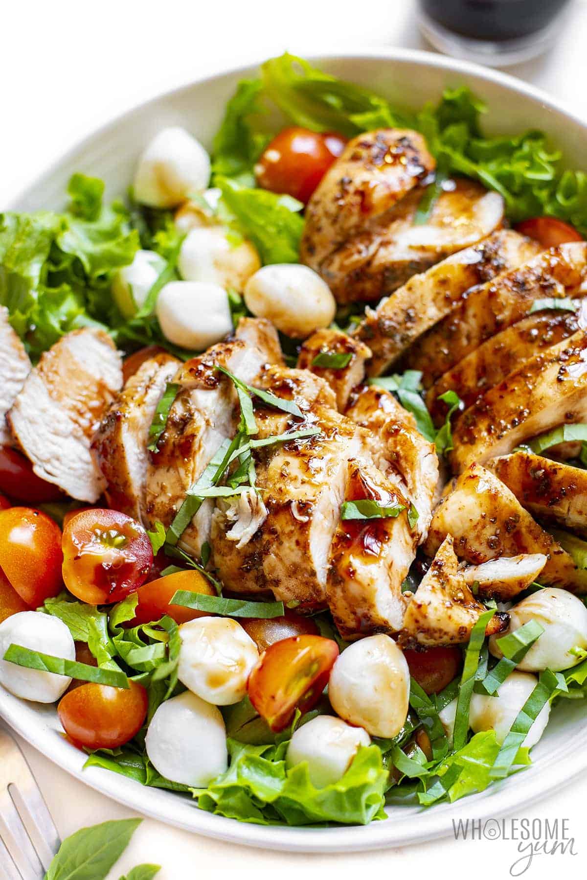Caprese salad with chicken next to basil and balsamic glaze.