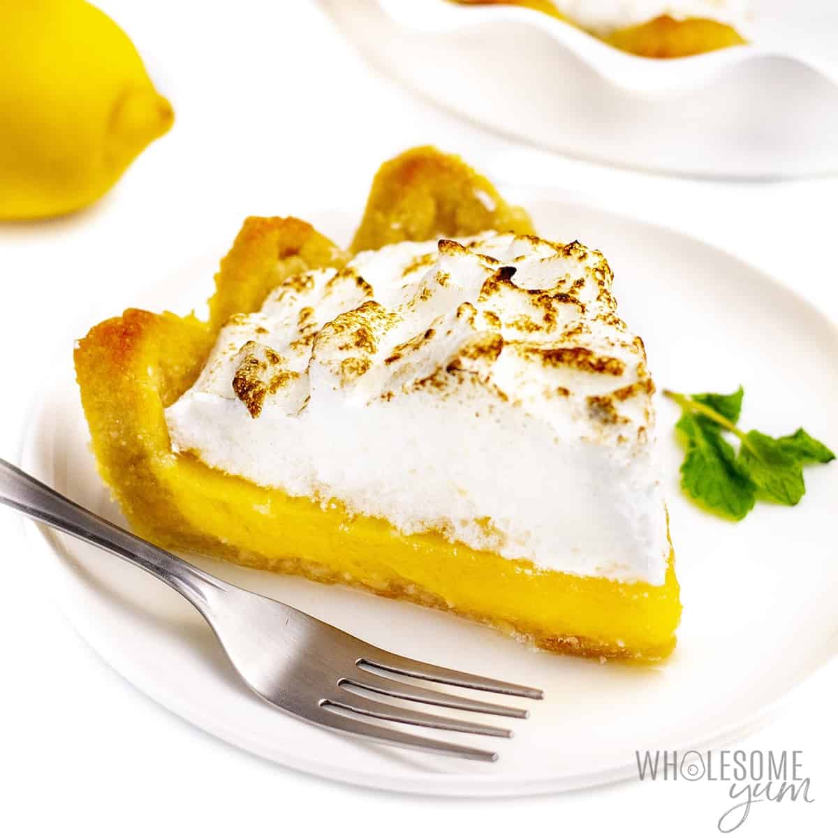 Slice of keto lemon meringue pie on a plate with a fork.