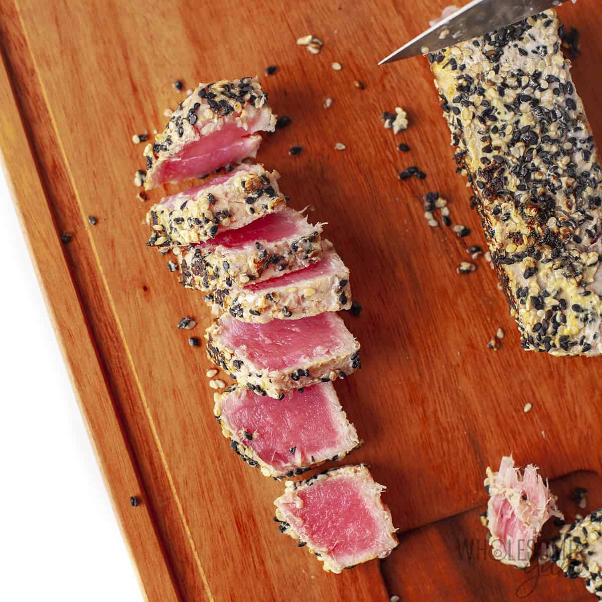 Tuna steak sliced on cutting board.
