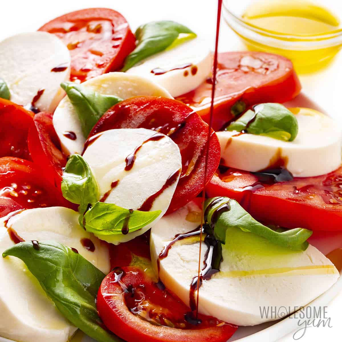 Caprese salad dressing drizzled over salad ingredients.