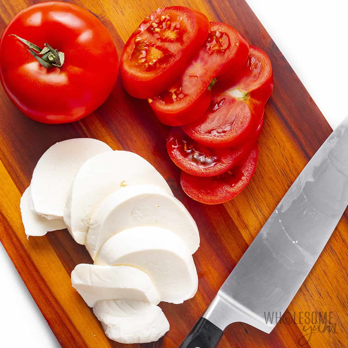 Sliced tomatoes and mozzarella on a cutting board.