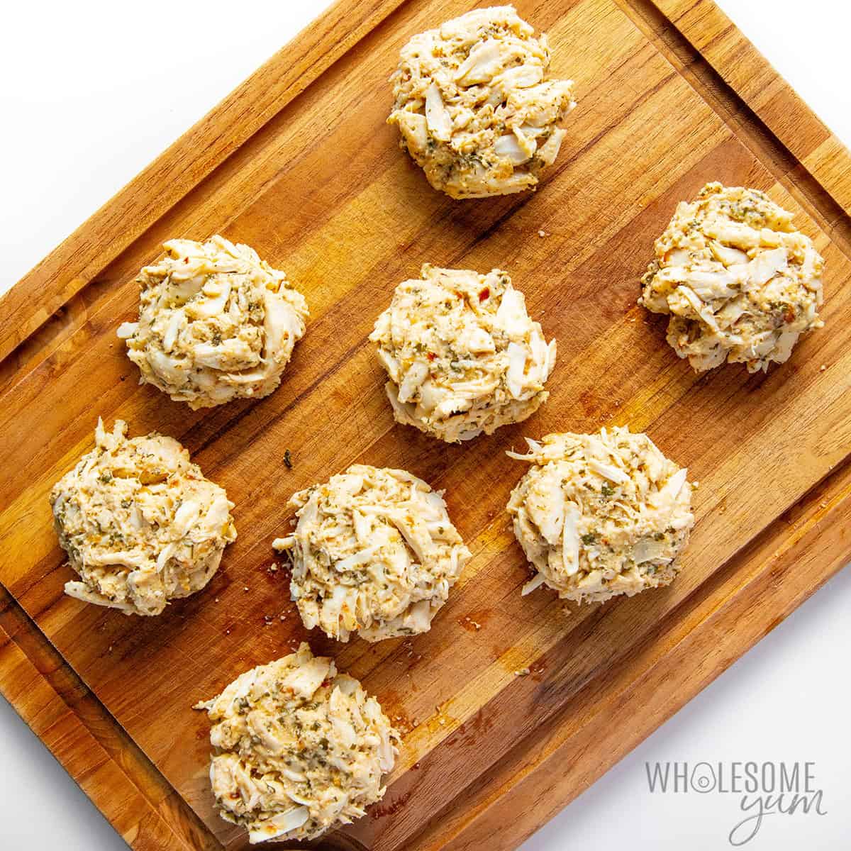 Raw crab cake patties on a cutting board.