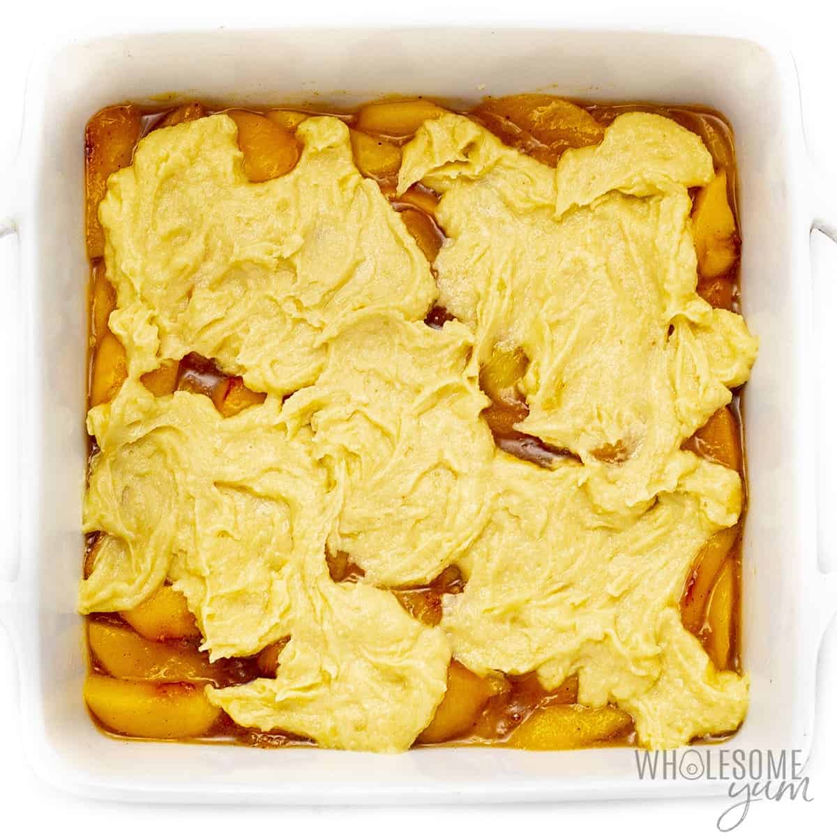 Healthy peach cobbler with batter spooned on top.