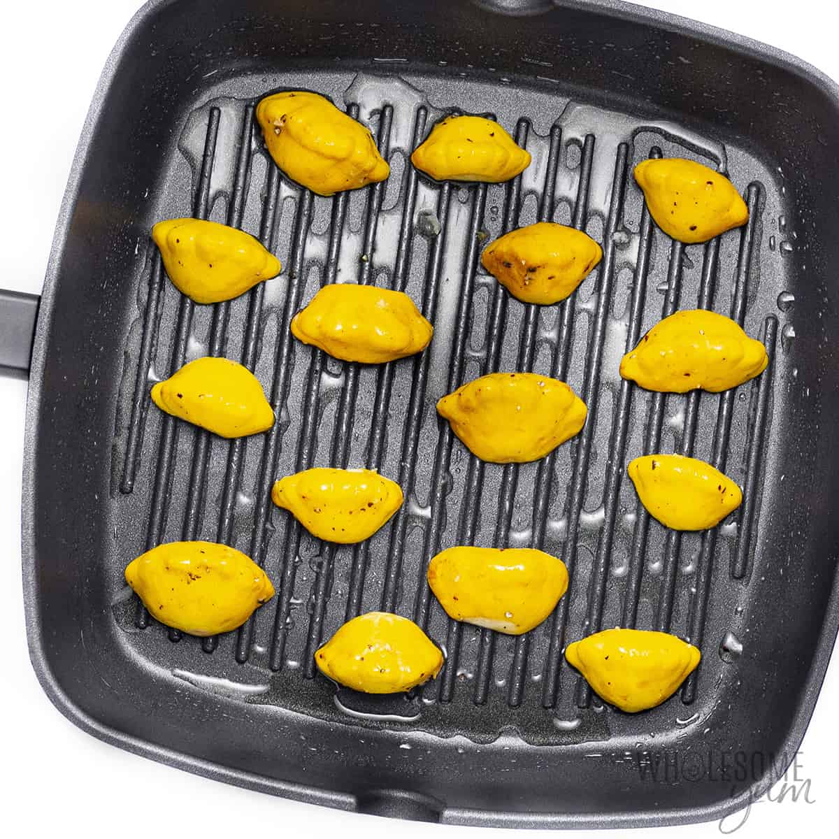 Uncooked patty pan squash in a grill pan.