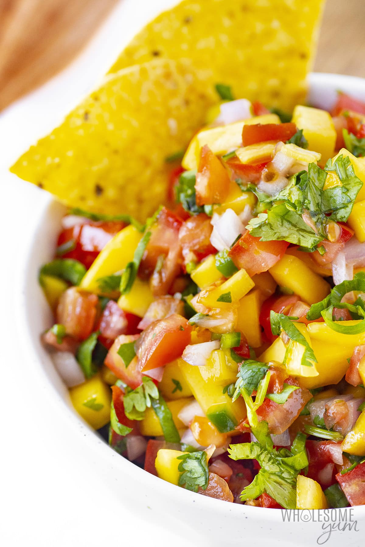 Mango salsa recipe in a bowl with two chips.