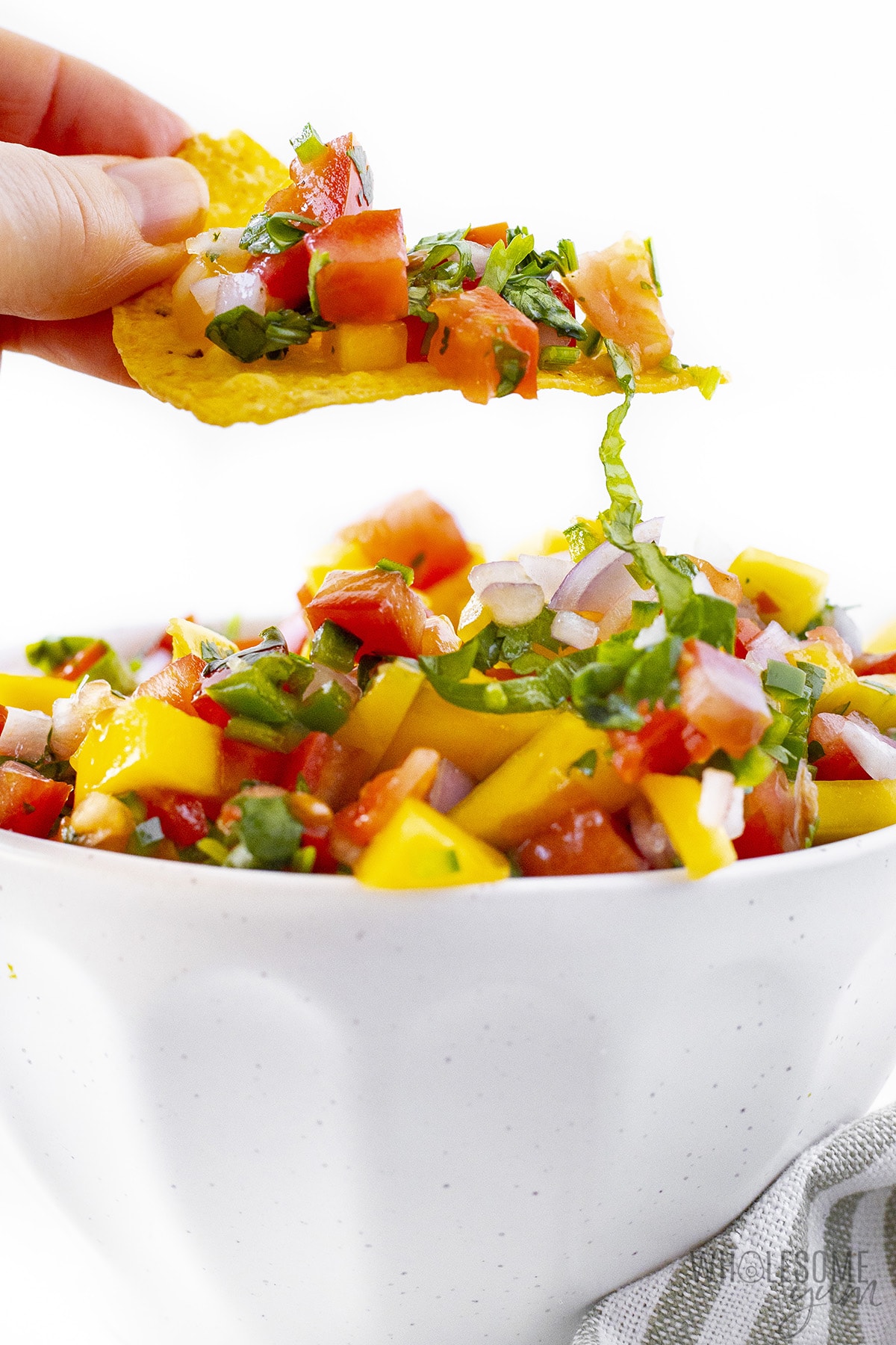 Chip holding a scoop of mango salsa.
