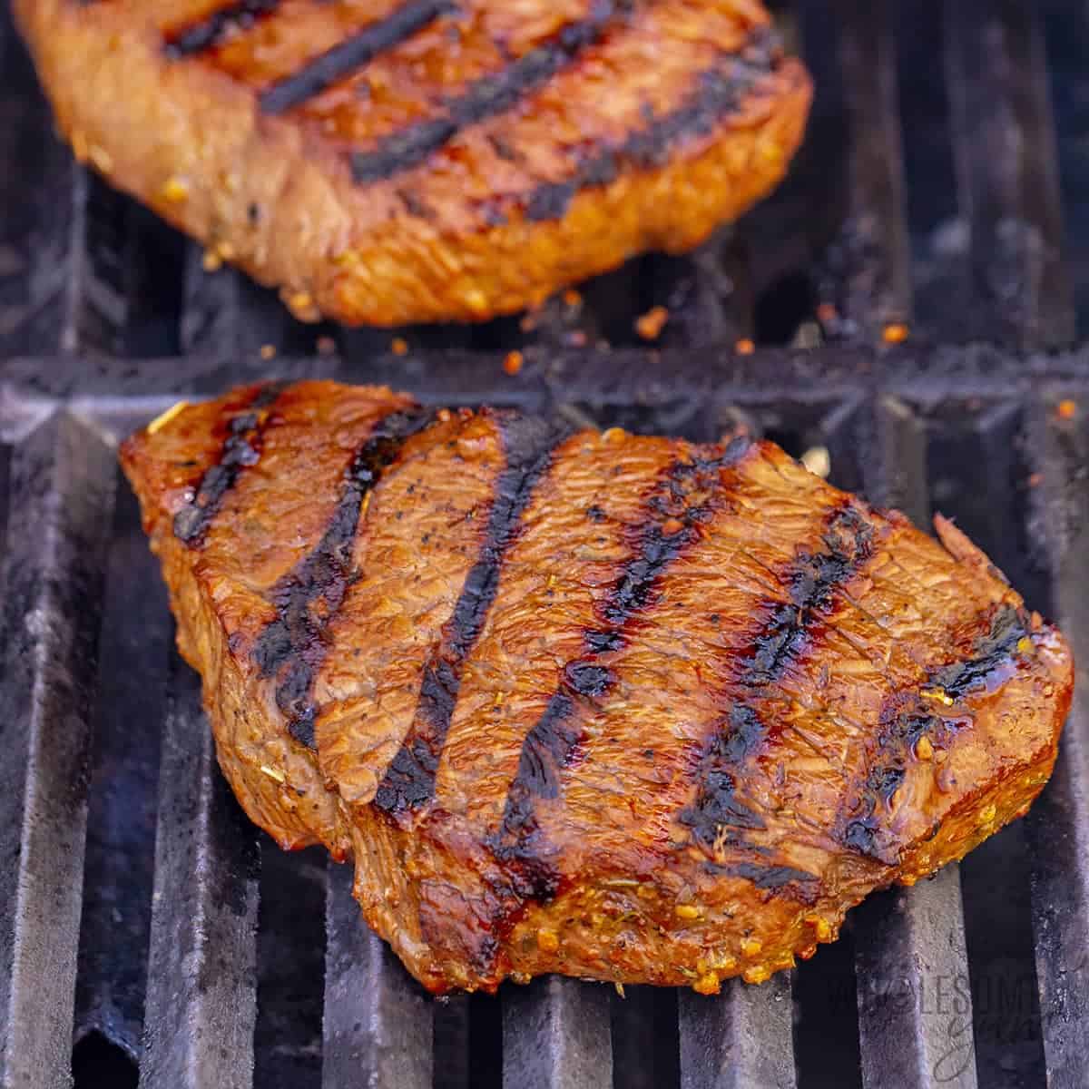 Seared steaks on grill grates.