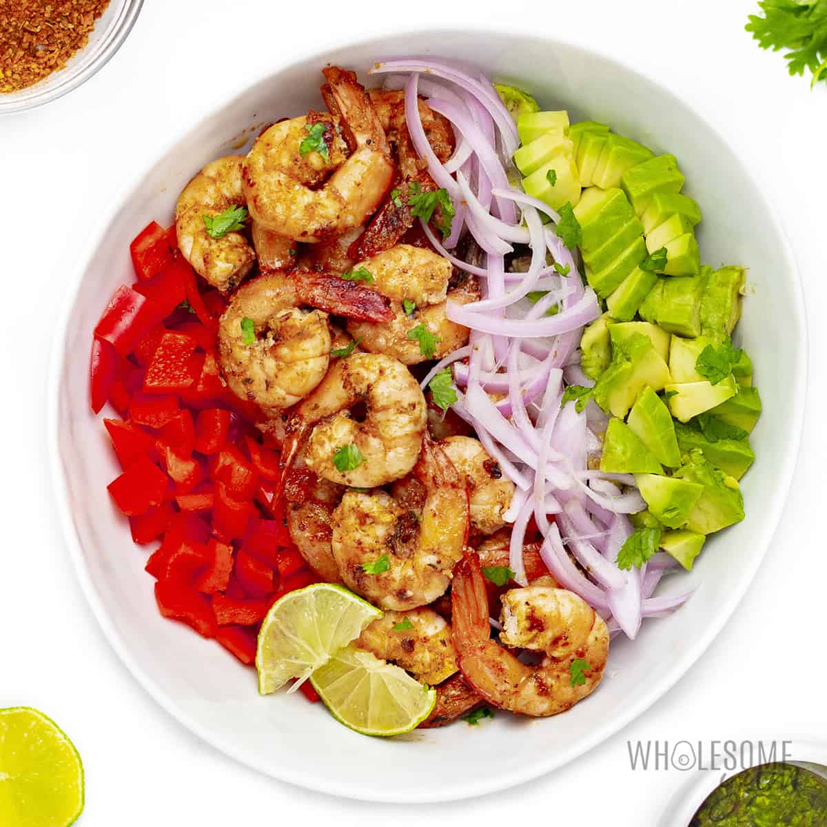 Shrimp and avocado salad ingredients in a bowl before tossing in dressing.