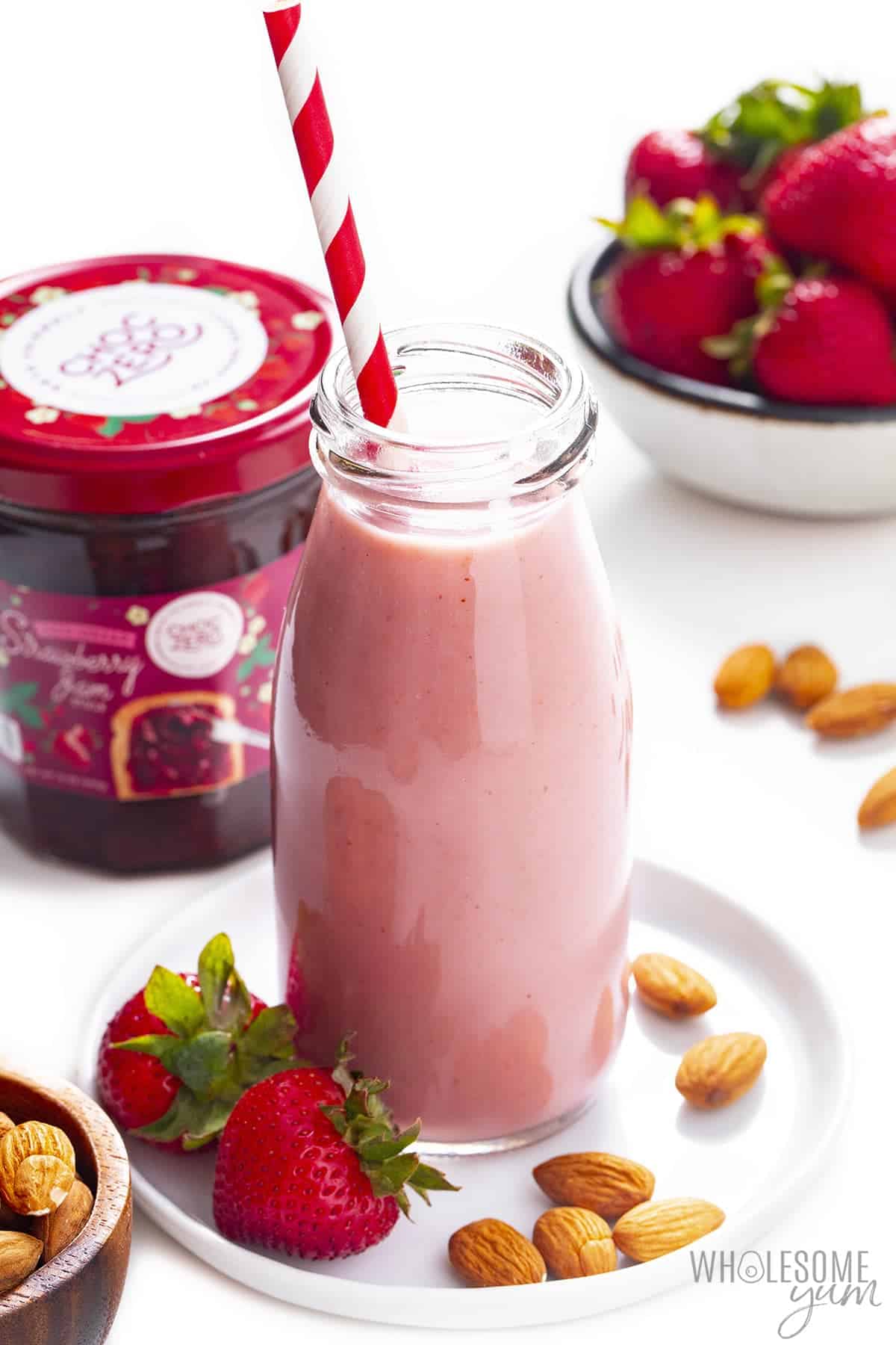 Strawberry almond milk in a glass bottle with straw and ChocZero strawberry preserves.