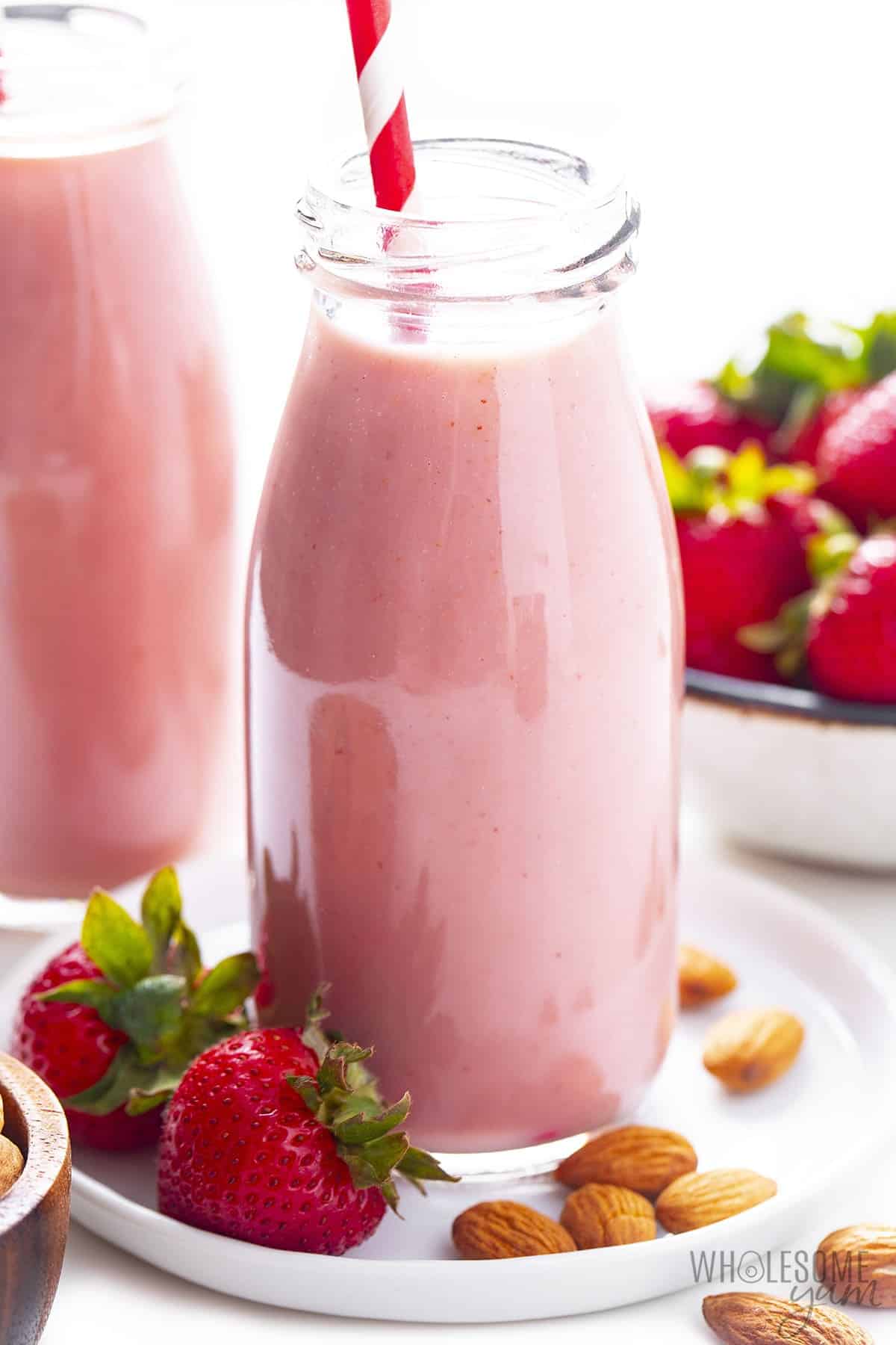 Glass bottle of strawberry almond milk with straw.