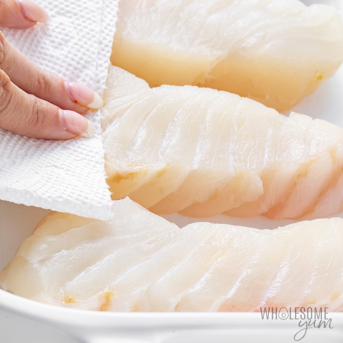 Drying halibut fillets with paper towels.