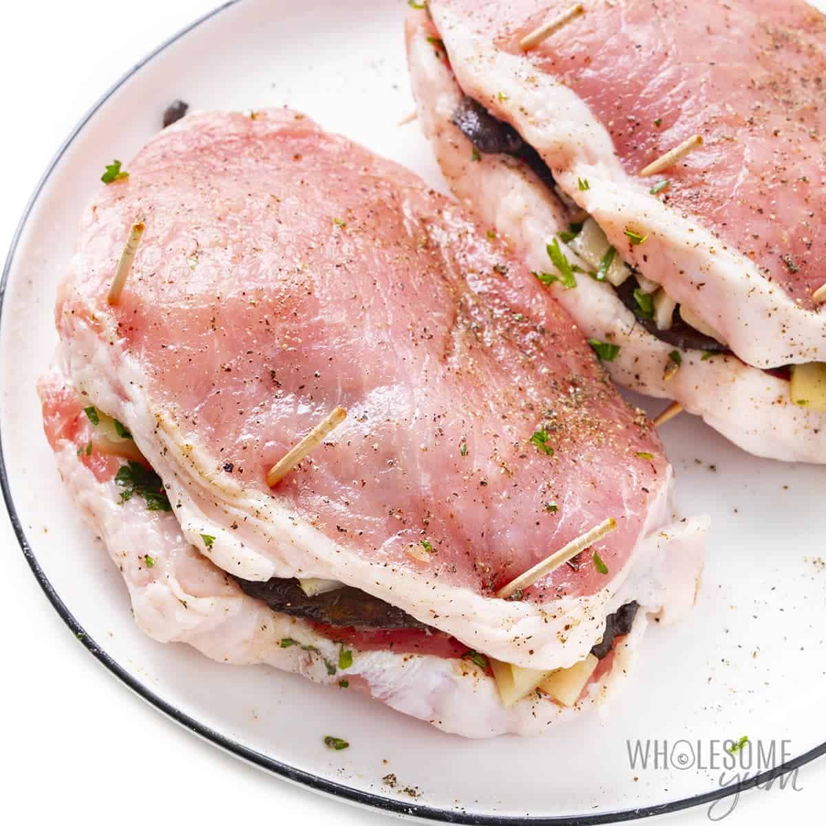 Raw pork chops stuffed with toothpicks to secure.