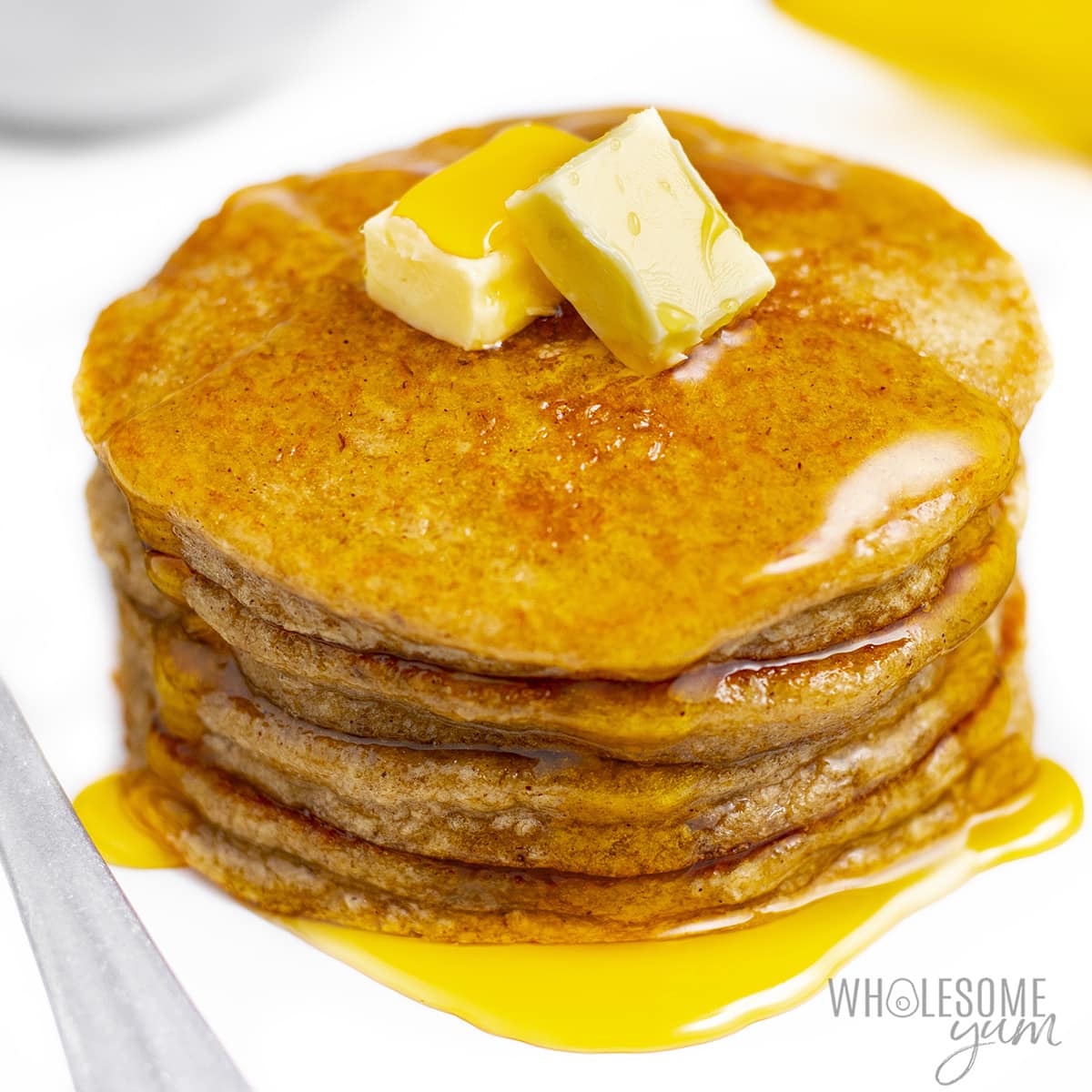 Oat banana pancakes in a stack with syrup and butter.