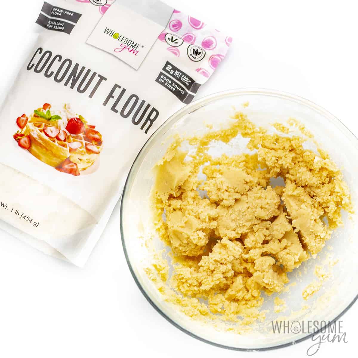 Cookie dough in a bowl next to Wholesome Yum Coconut Flour bag.