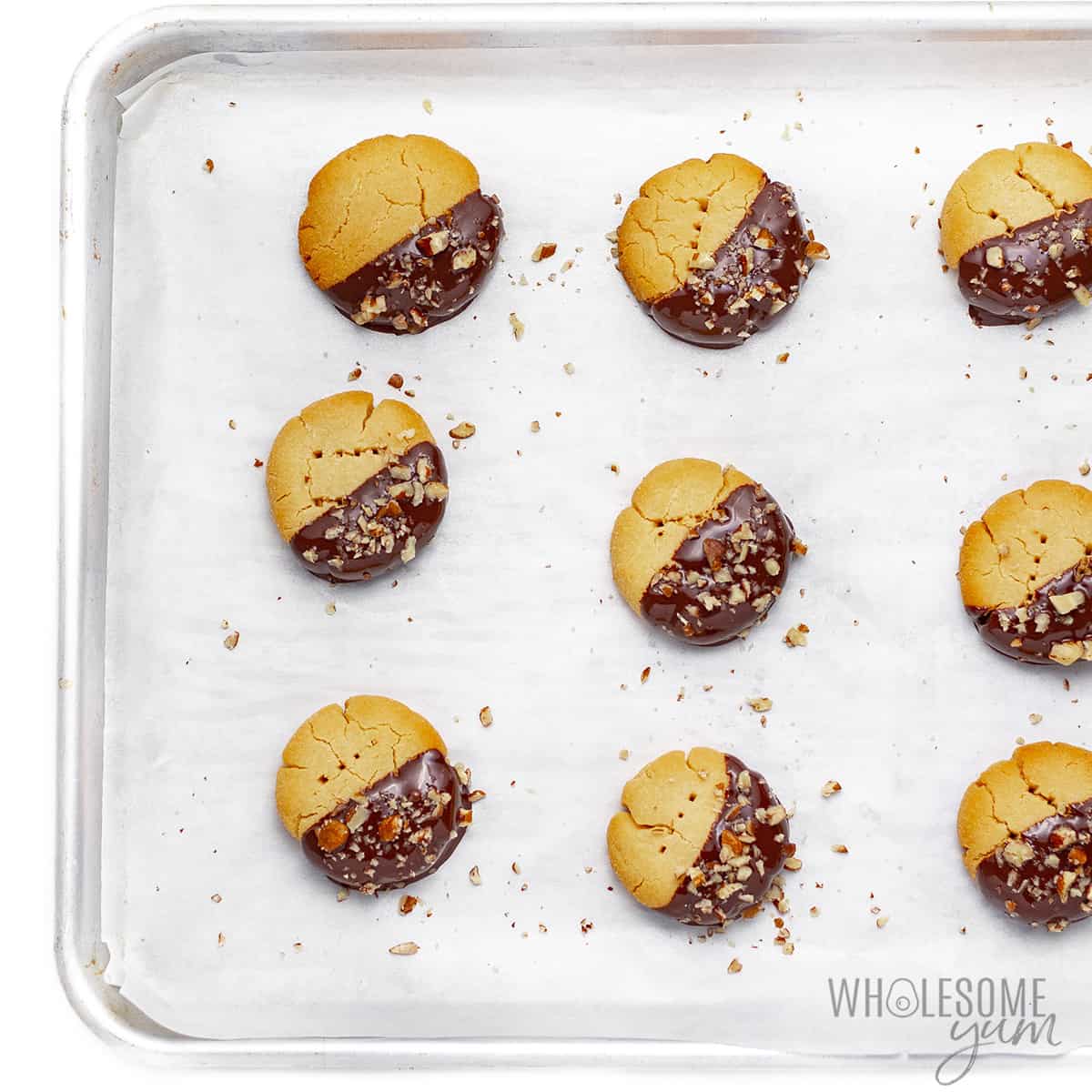 Coconut flour shortbread cookies on baking sheet with nuts sprinkled on top.