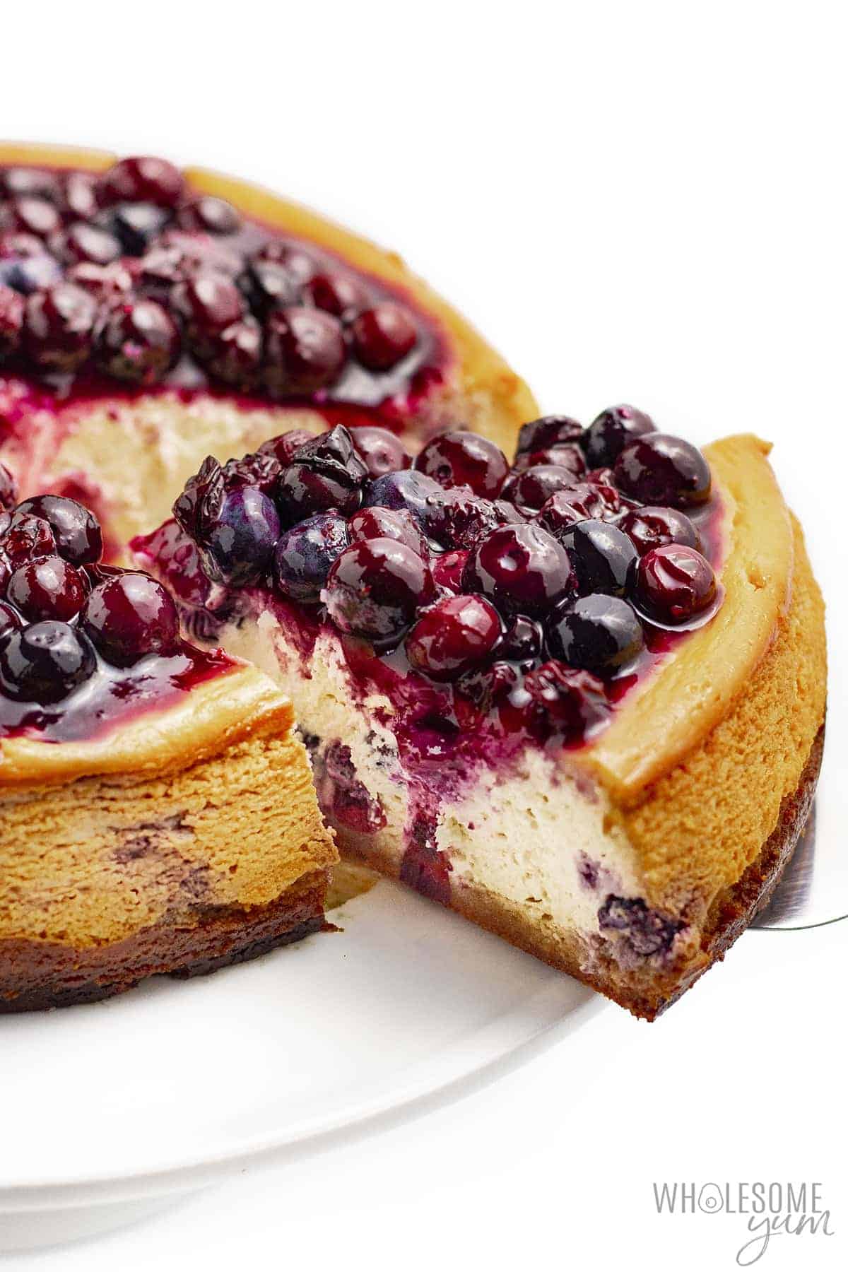 Slice of low carb blueberry cheesecake coming out of whole cake.
