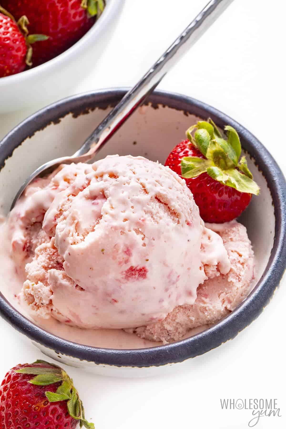 Side view of ice cream in a dish with strawberry garnish.