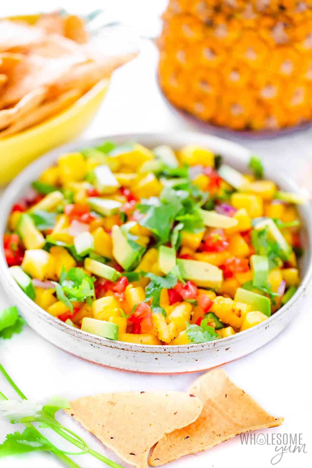 Pineapple salsa recipe next to chips and fresh pineapple.