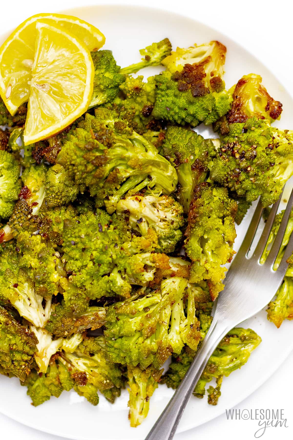 Roasted romanesco broccoli on a plate with lemon.