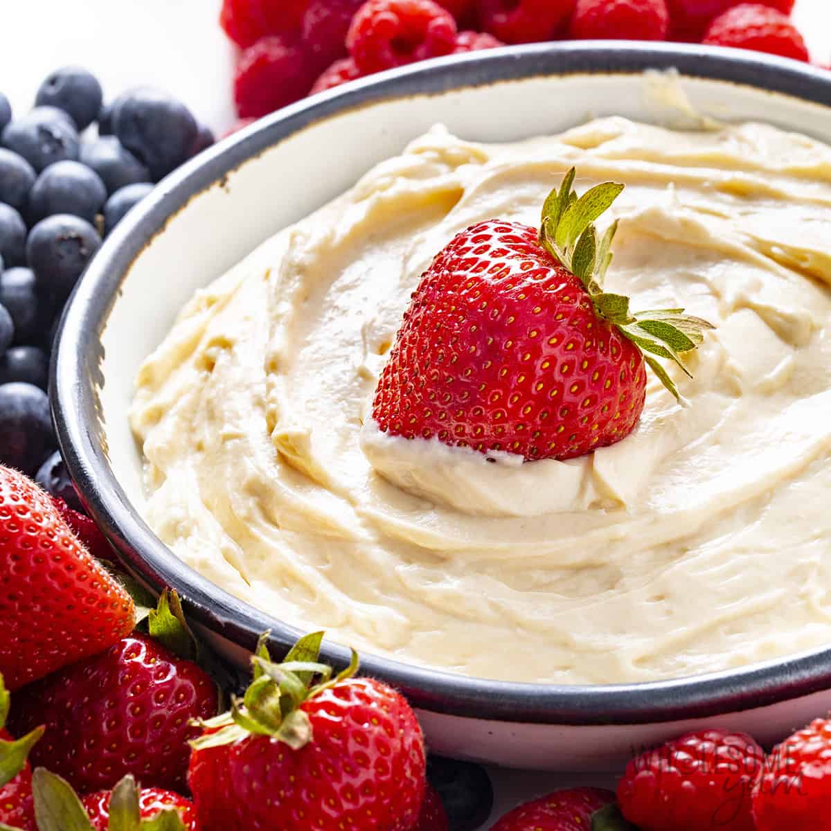 Close up of strawberry in healthy fruit dip next to berries.