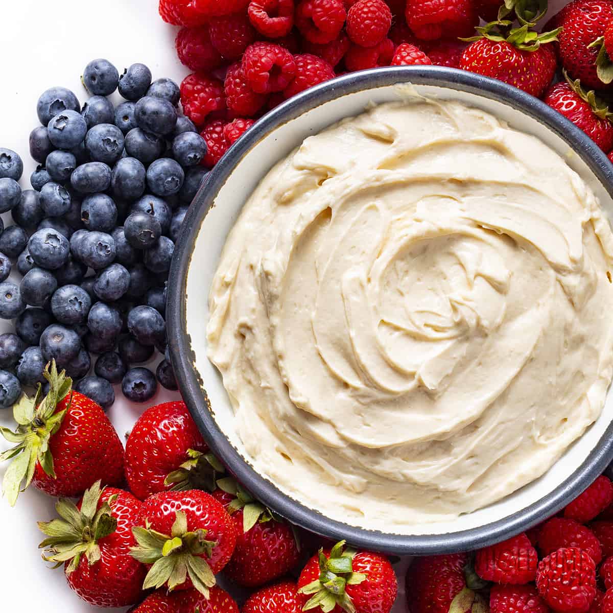 Healthy fruit dip in a bowl next to berries.