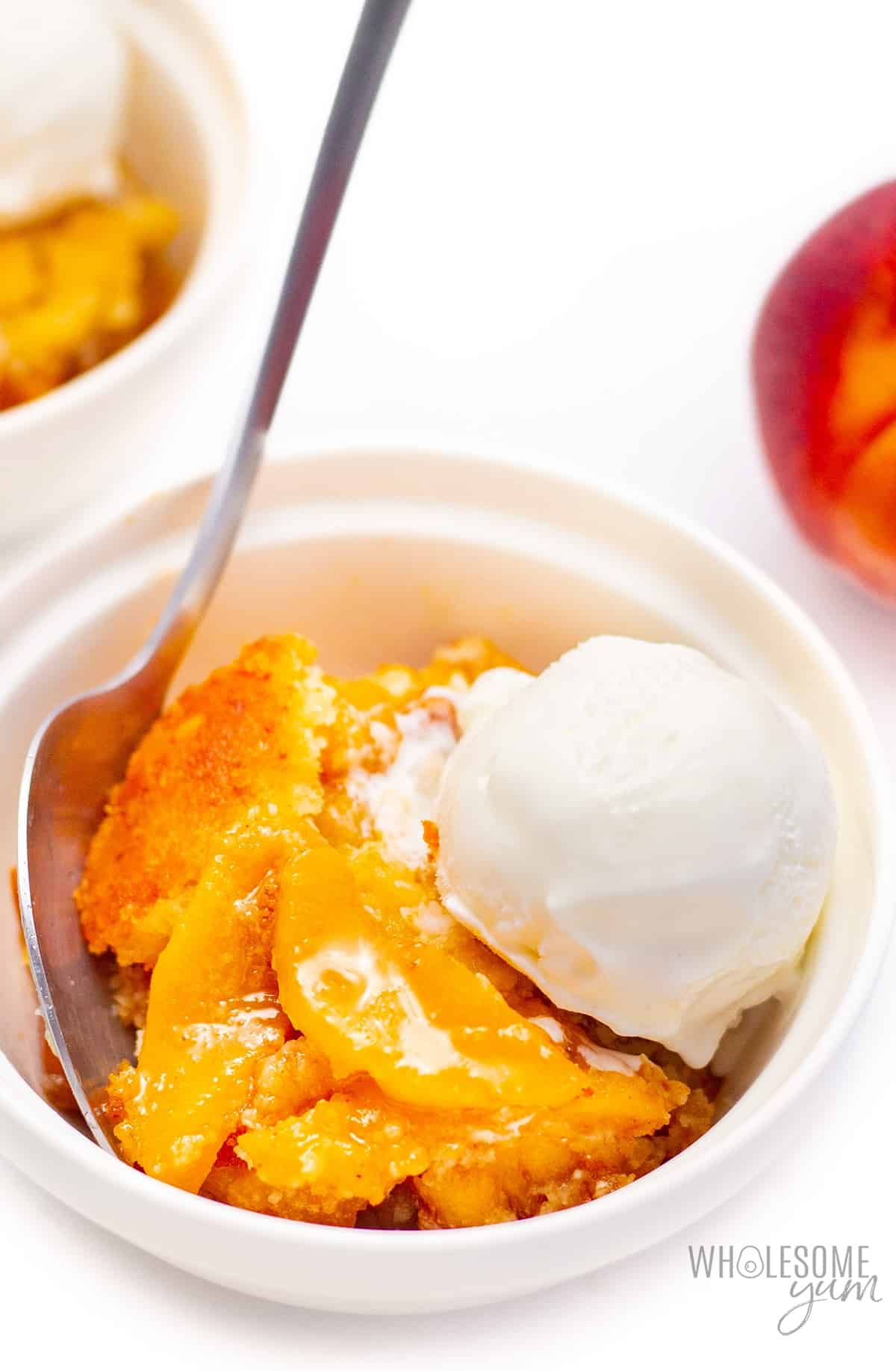 Sugar-free peach cobbler in bowl with spoon.