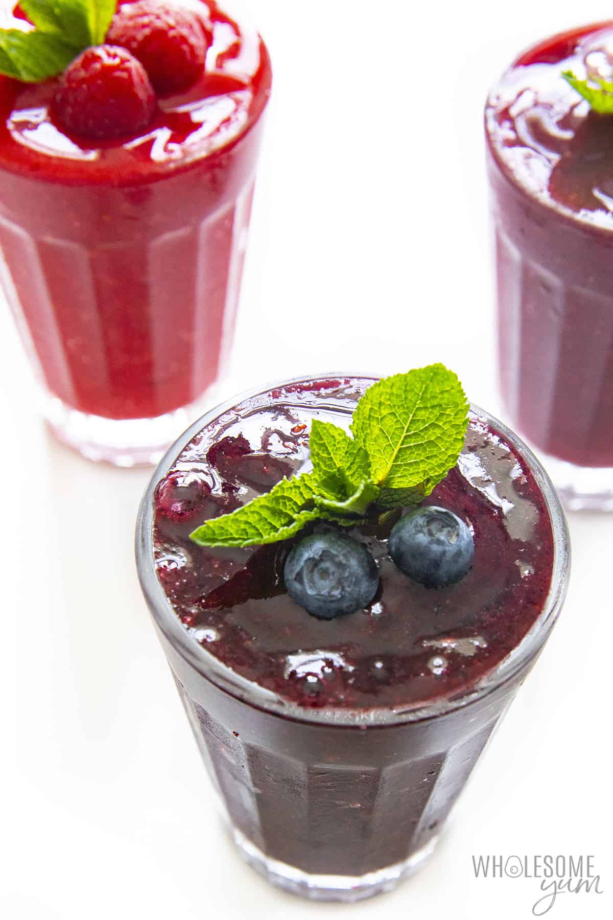 Sugar free slushie flavors in glasses with fresh berries on top.