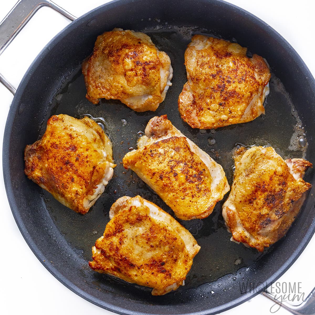 Pan fried chicken thighs in skillet.