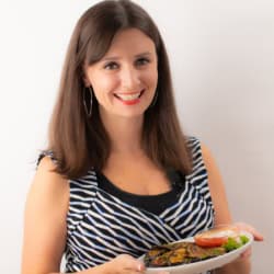 Maya holding her roasted eggplant recipe on a plate.