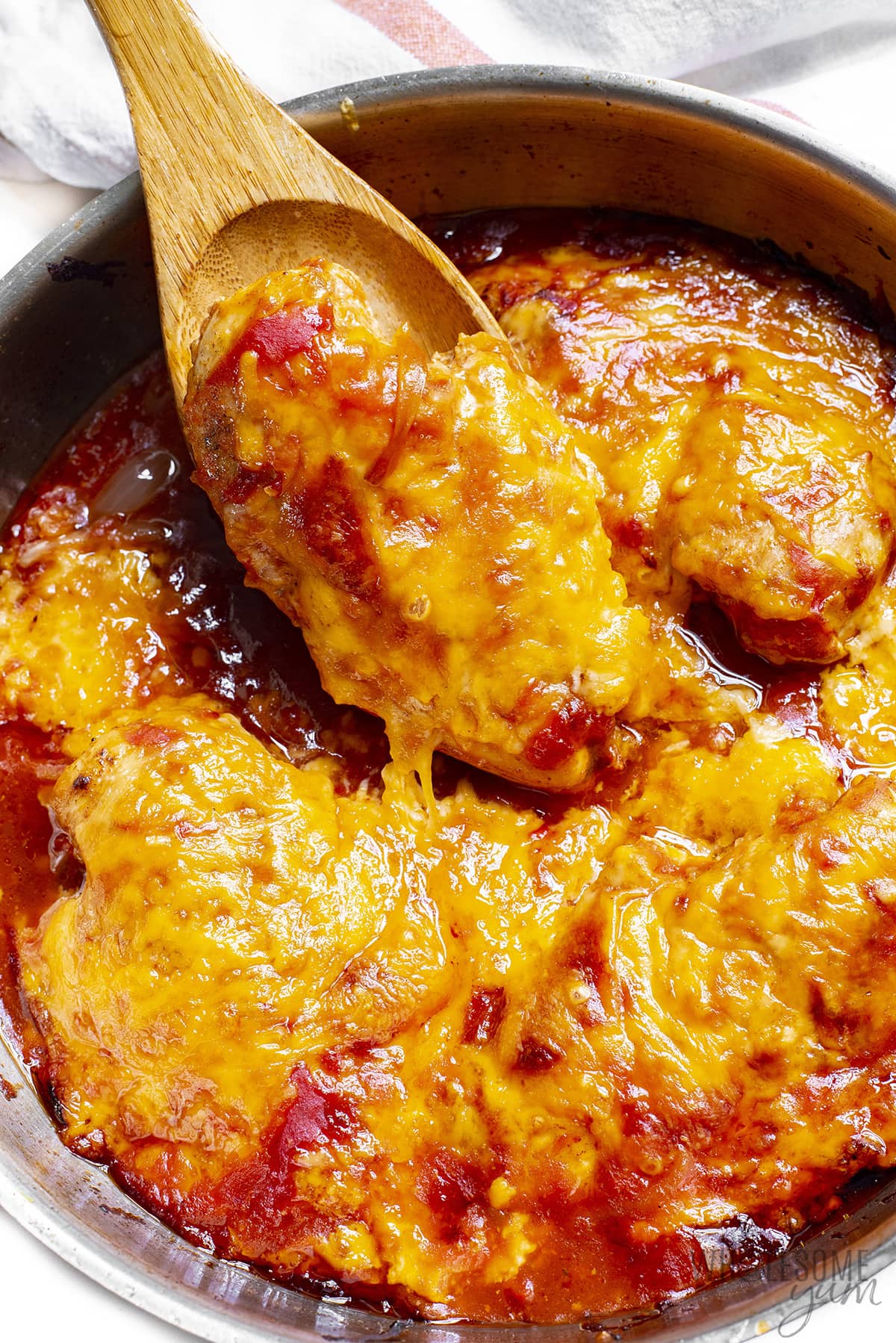Baked salsa chicken with spoon removing one chicken breast from the pan.