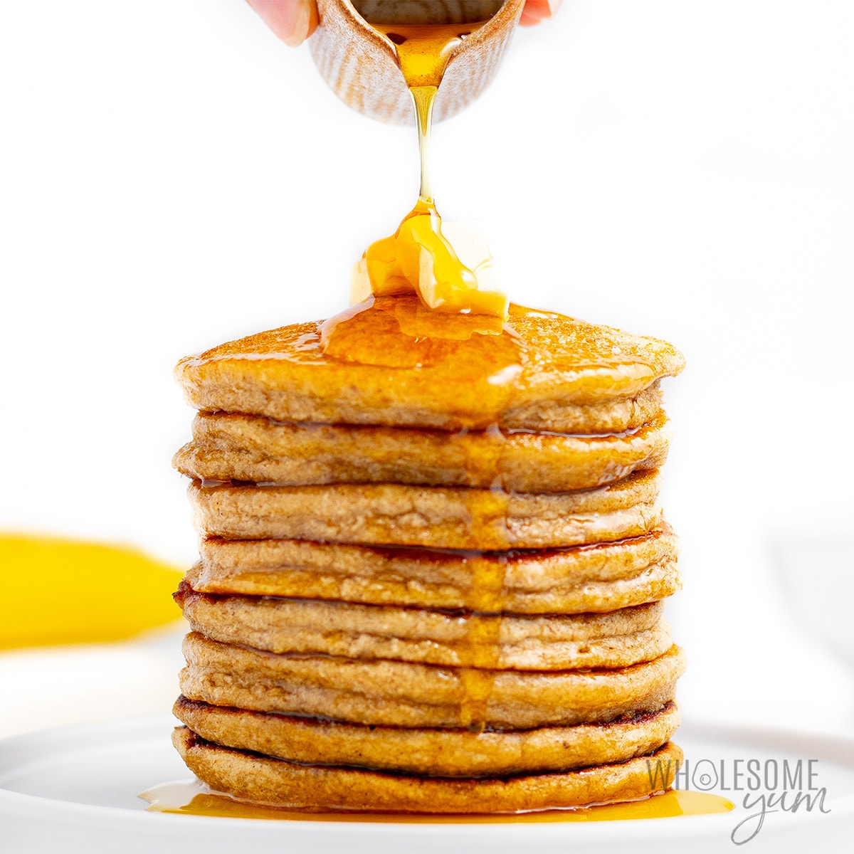 Banana oat pancakes stack with maple syrup being drizzled over it.