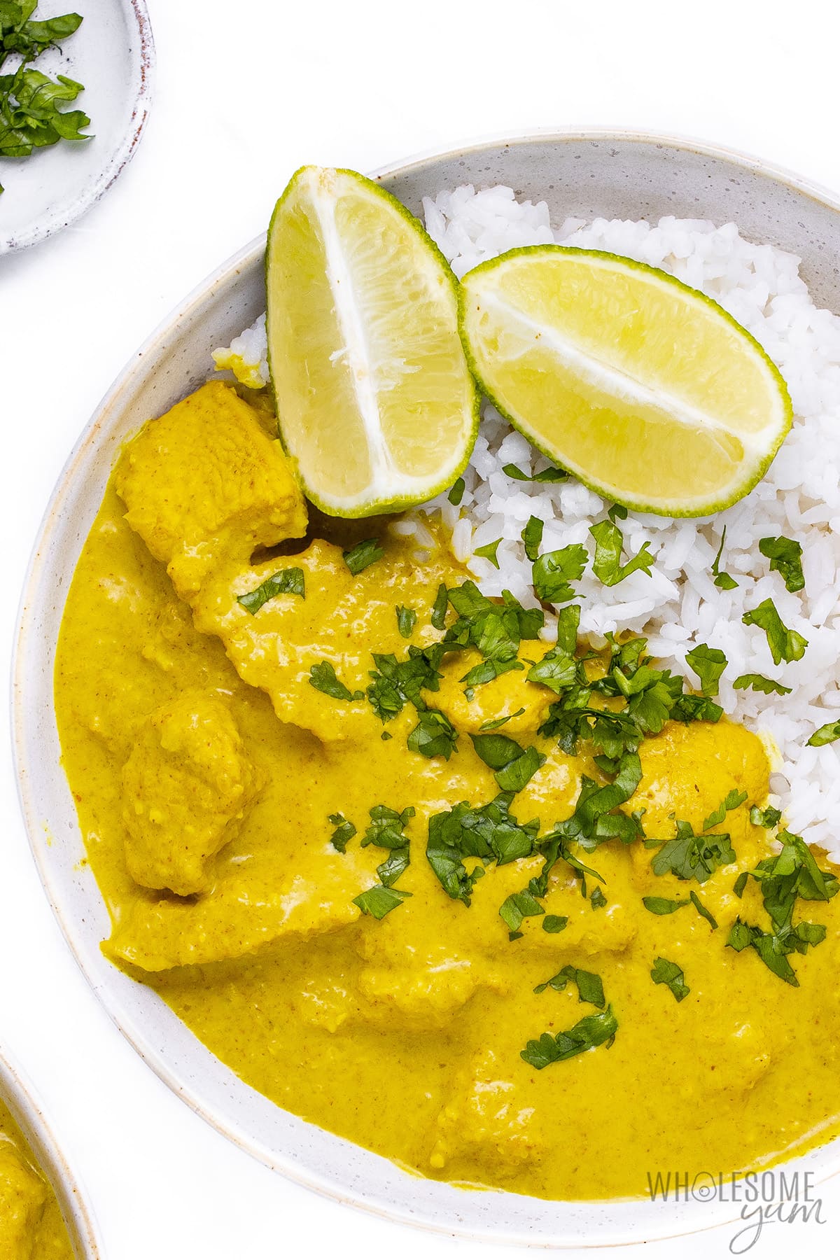 Recipe for korma chicken on a plate with lime wedges.