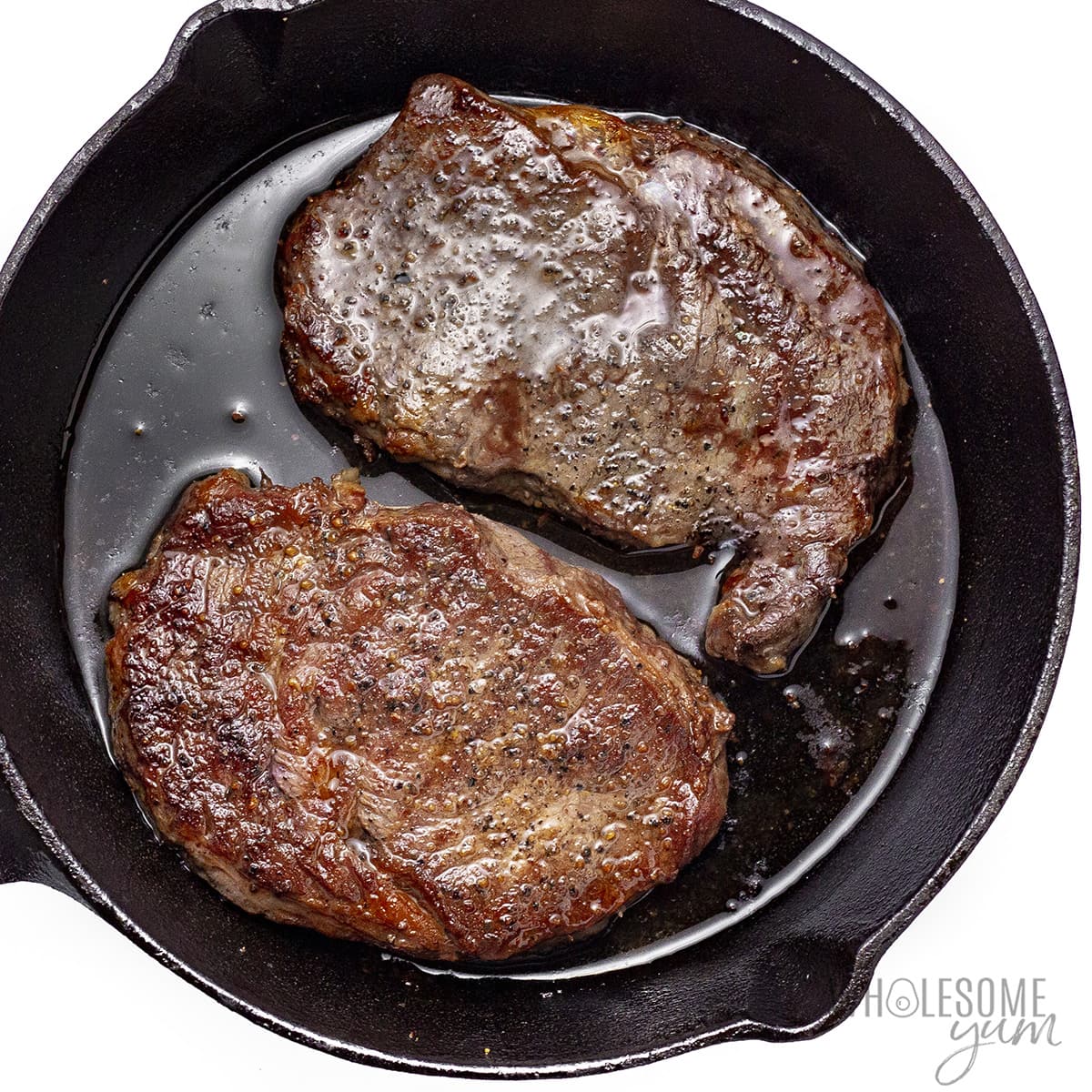 Chuck's eye steak fully cooked in a frying pan.