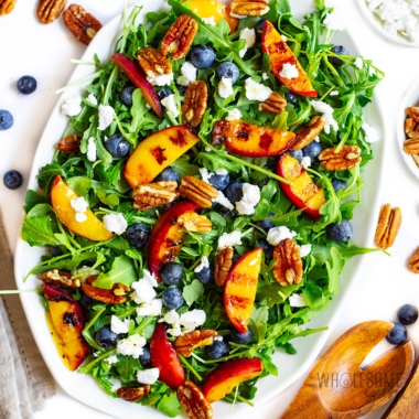 Grilled peach salad recipe with wooden spoons and scattered ingredients.