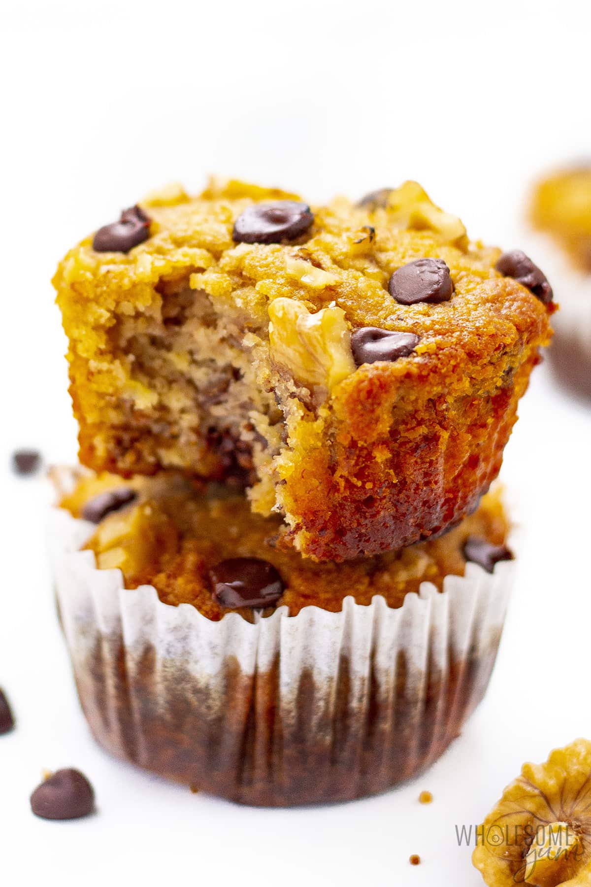 Two stacked healthy banana muffins with a bite from the top.