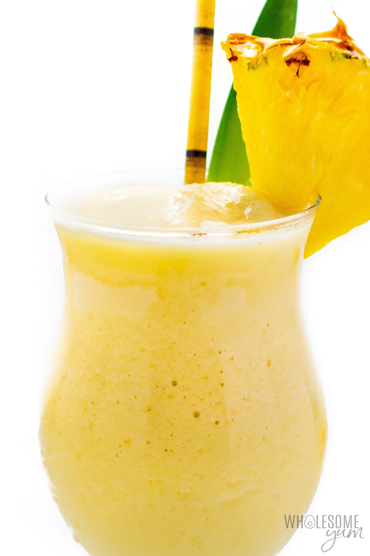 Frozen pina colada with straw and fresh pineapple wedge.