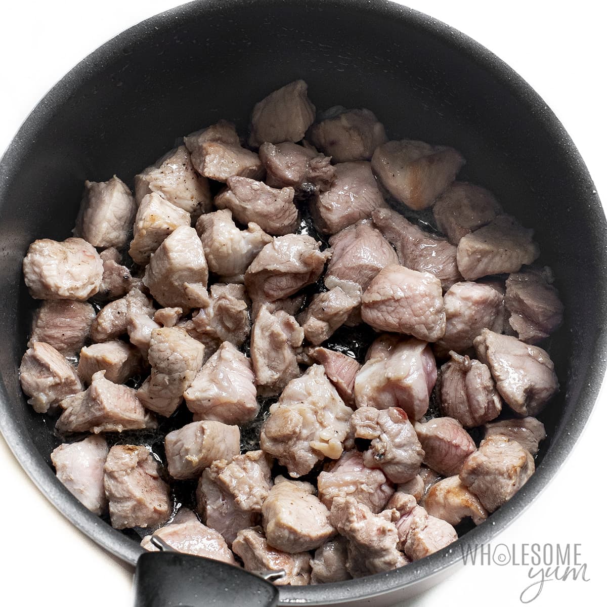 Pork stew meat searing in pot.