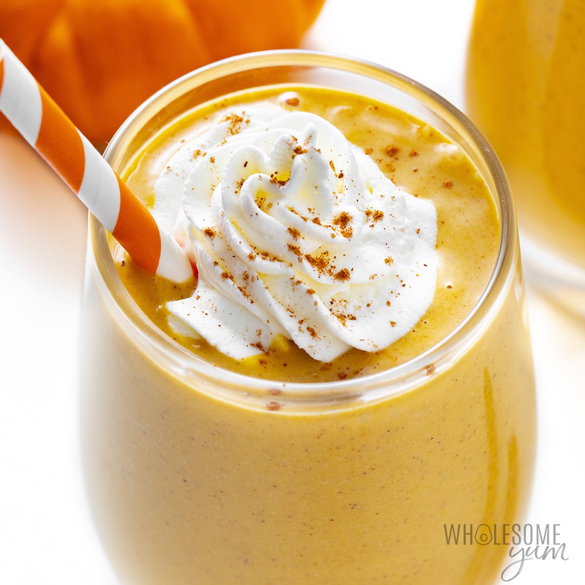 Pumpkin smoothie in a glass with a straw.