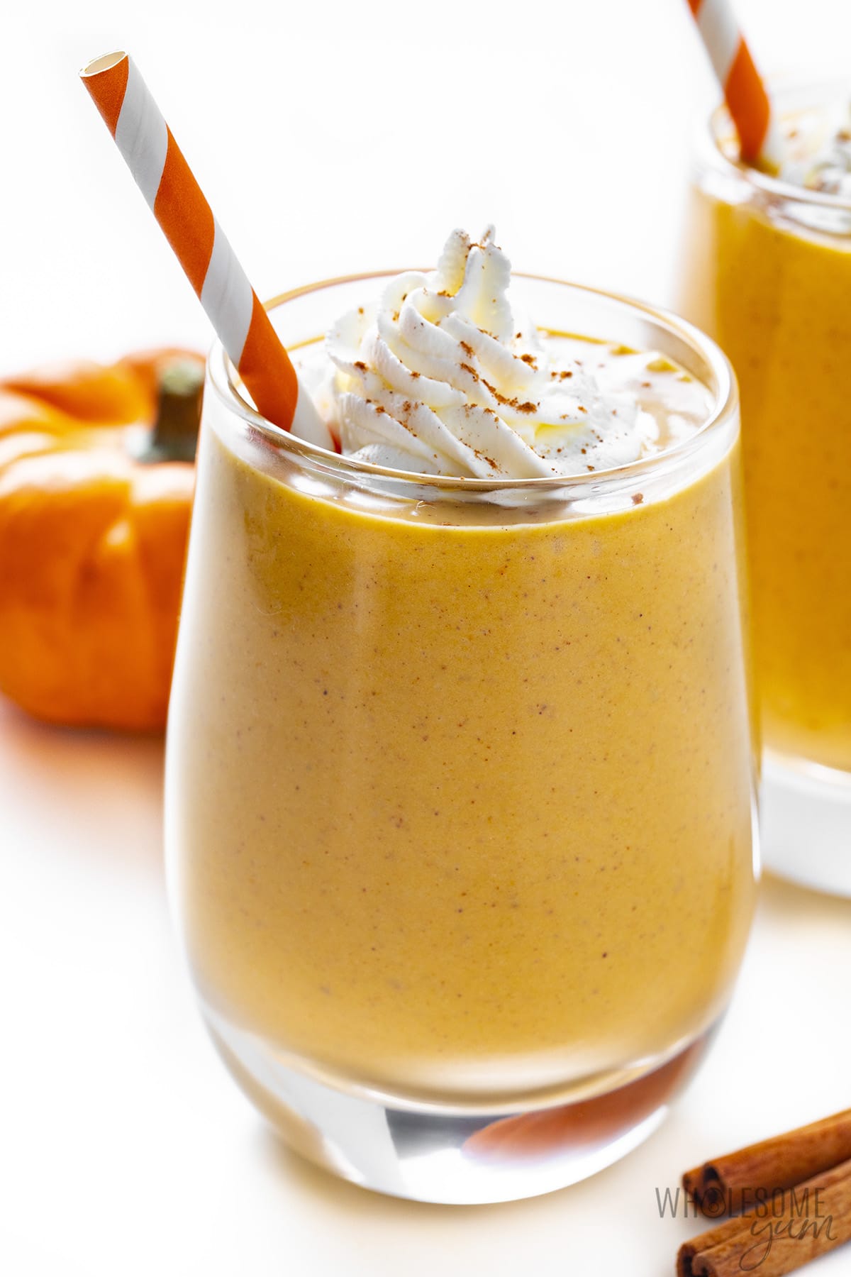 Side view of pumpkin pie smoothie in a glass with whipped cream.