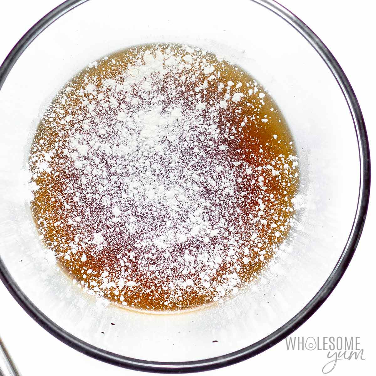 Xanthan gum sprinkled over syrup in a bowl.