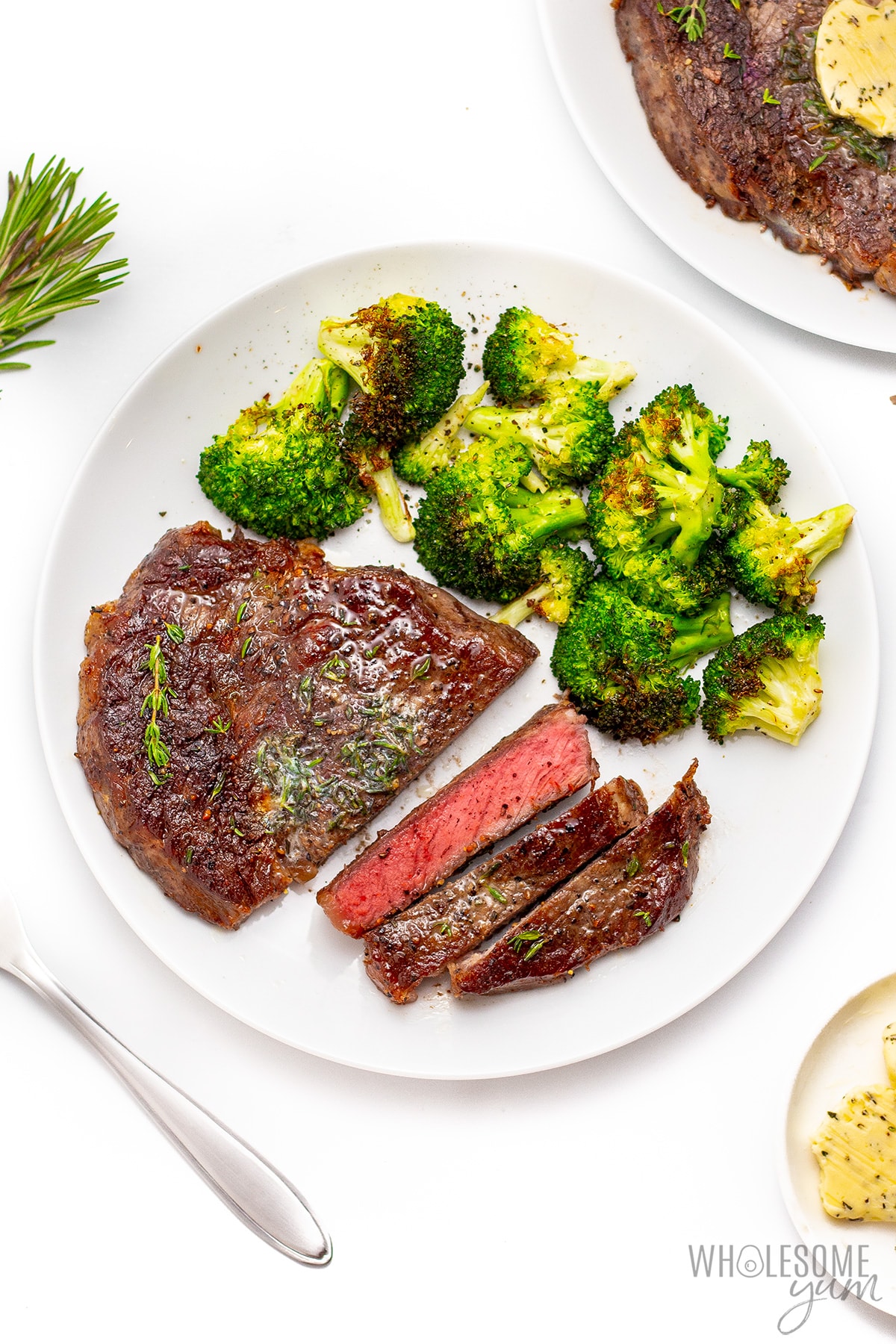 Cut steak on a plate with broccoli on top.