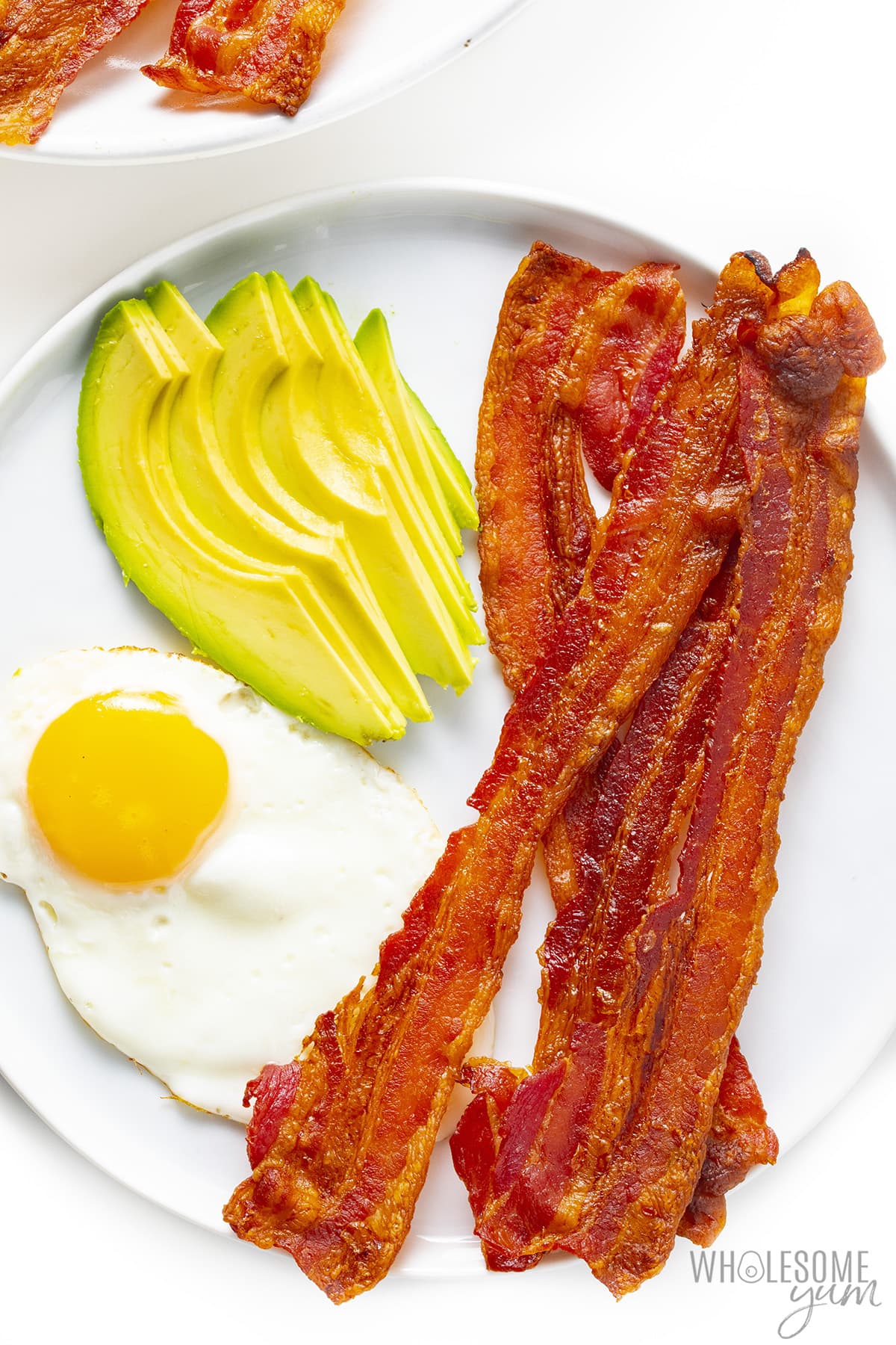 Breakfast plate: bacon, fried egg, and avocado.