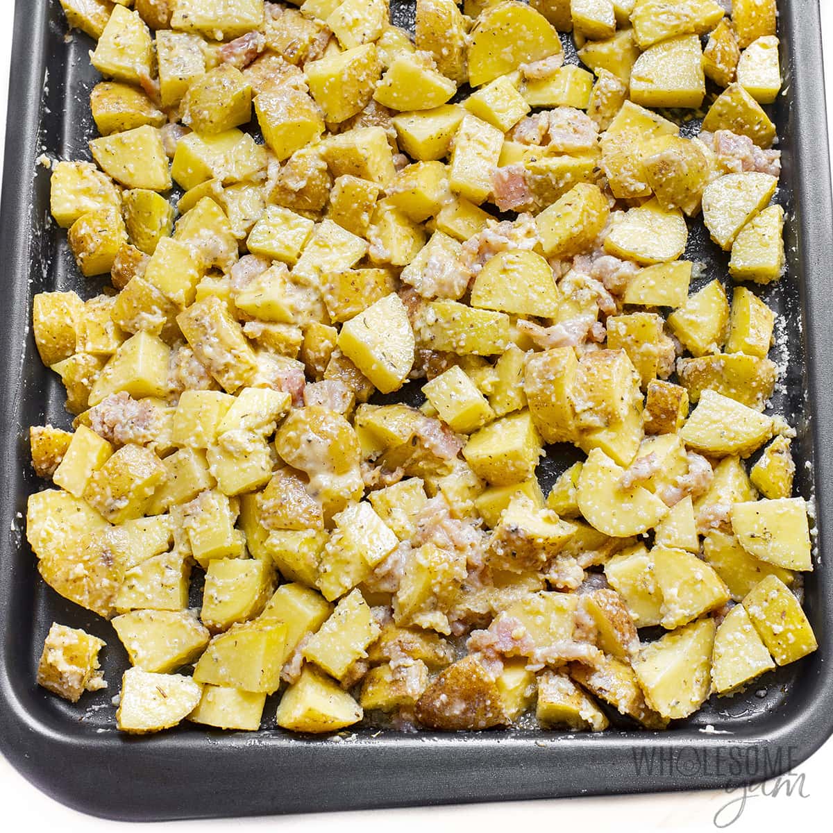 Potatoes with seasonings on sheet pan.